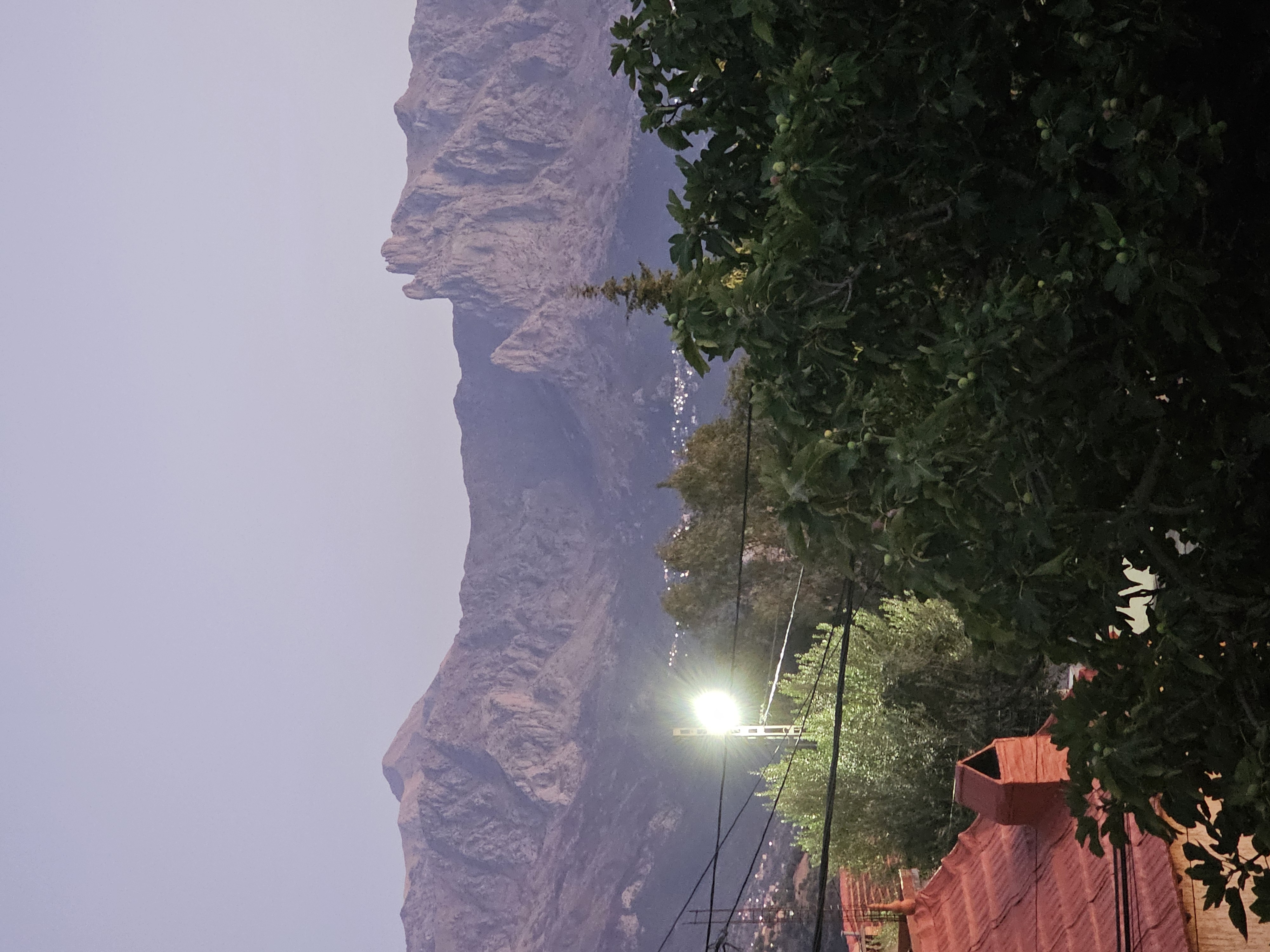 Montagnes au crépuscule, au-dessus des arbres et des lumières du village.