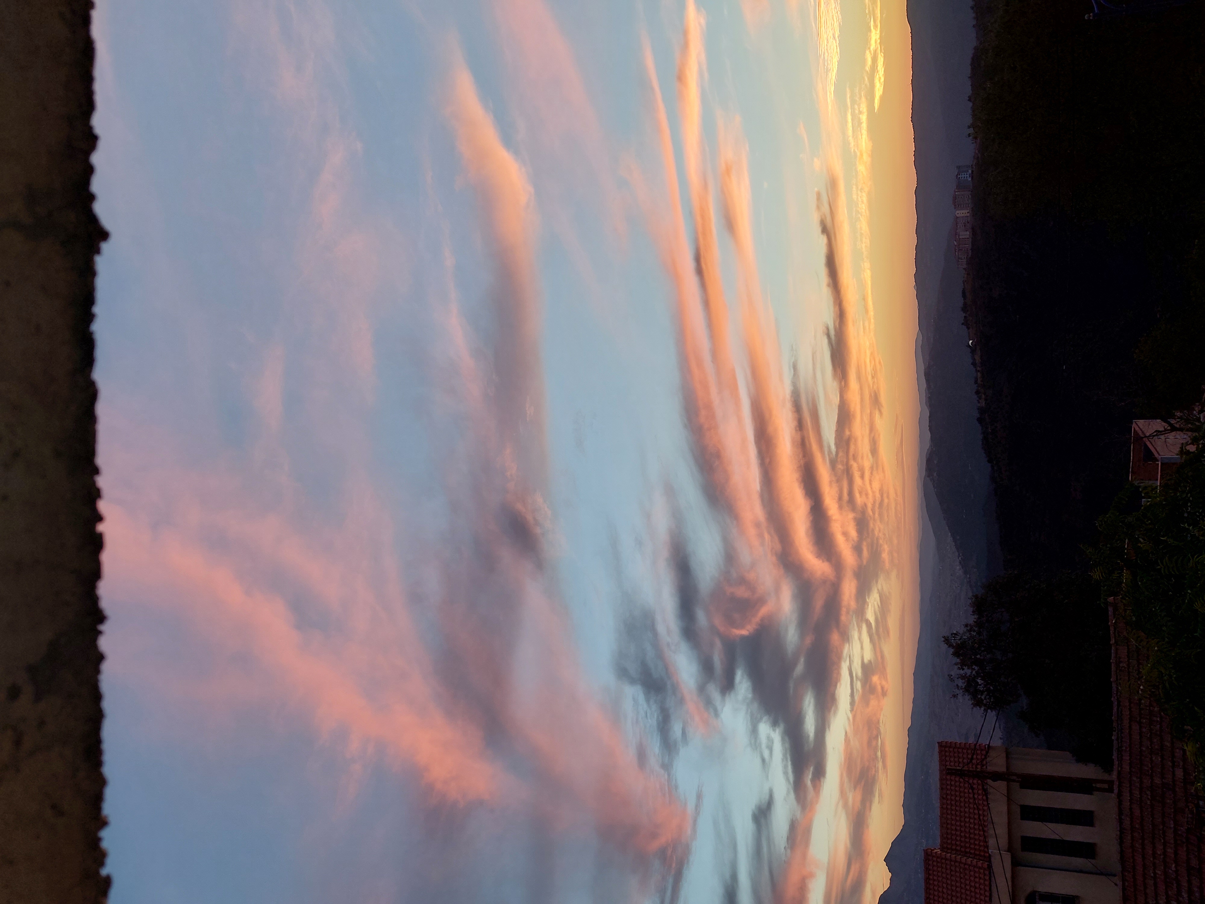 Nuages roses au-dessus des montagnes et des toits au coucher du soleil.