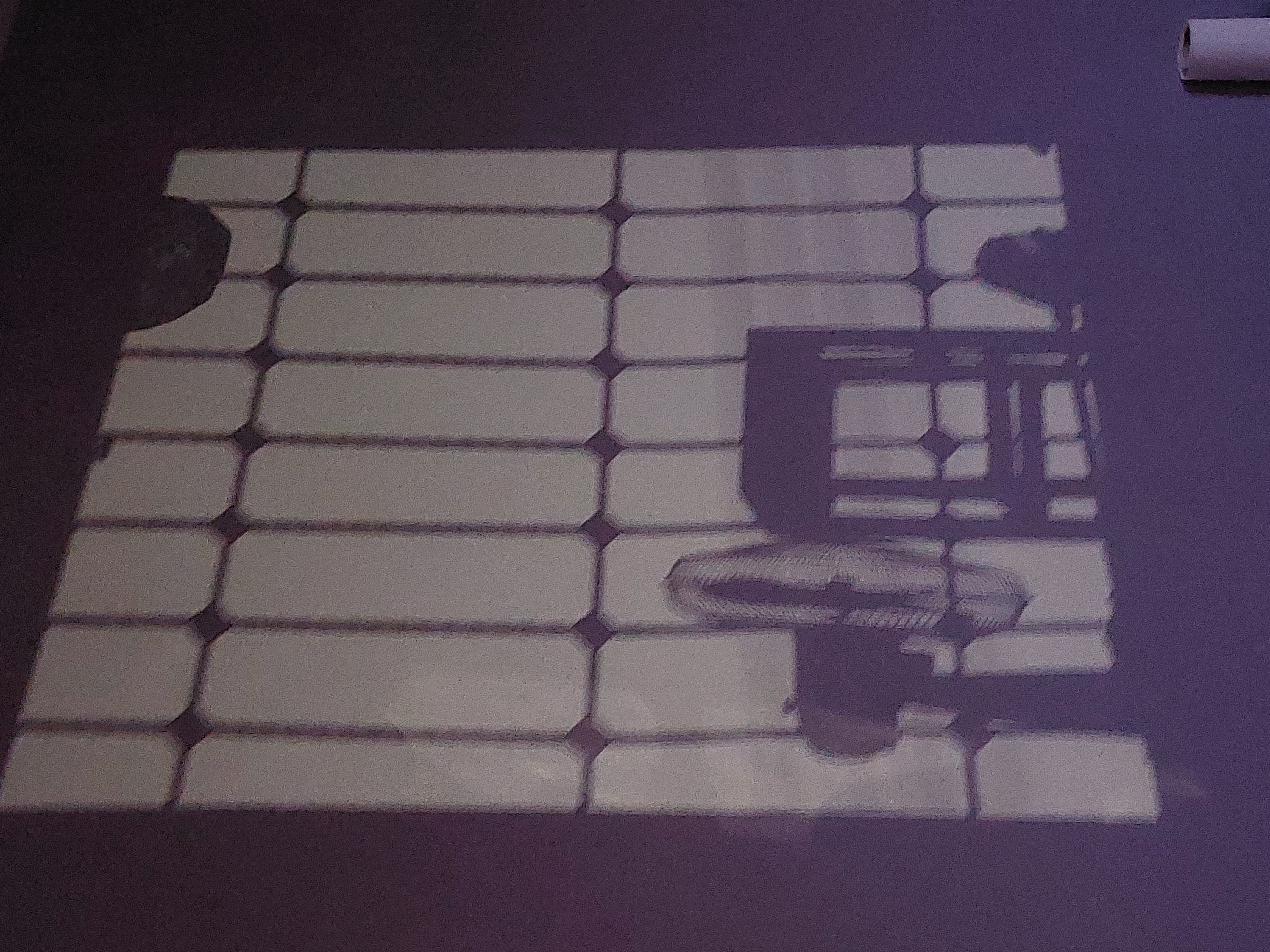 Les ombres d’une fenêtre, d’un ventilateur et d’une chaise sur un mur.